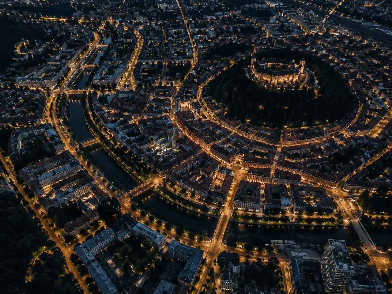 Nočni pogled na Ljubljano z osvetljenimi ulicami in reko Ljubljanico